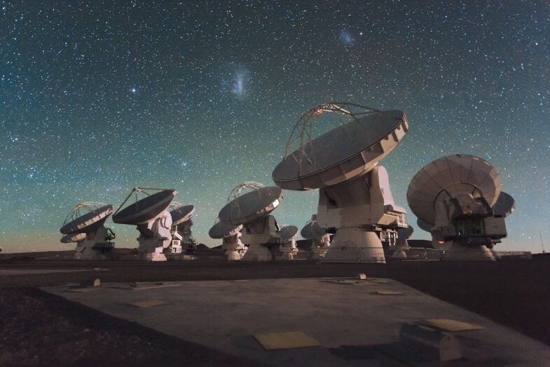 A group of large radio telescope dishes against a starry night sky