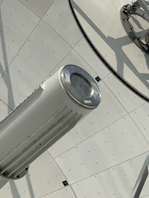 A close-up on an antenna's feed, with a round metal plate at the end