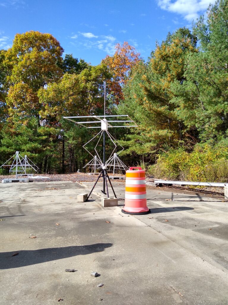 an antenna on a concrete pad next to an orange barrel