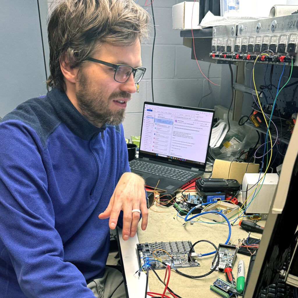 A male engineer looking at a screen on a workbench