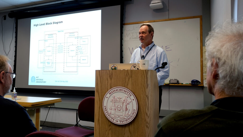 A man giving a presentation behind a lecturn labeled "Massachusetts Institute of Technology," with a slide labeled "High-level block diagram"