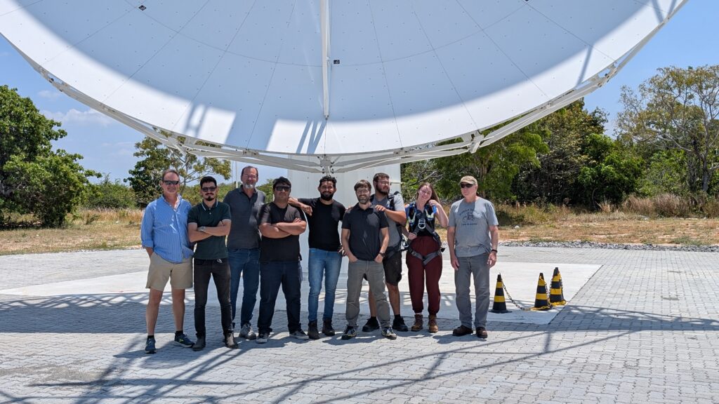 A group of people standing outside under the bottom of a radio telescope dish
